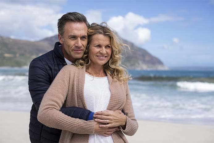 Casal de meia idade abraçados contemplando o mar