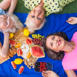 Uma variedade de frutas frescas e coloridas, vegetais e nozes, representando as fontes naturais de vitaminas e minerais essenciais, ao lado de suplementos em cápsulas e comprimidos da Órion Farmácia de Manipulação, ilustrando a importância da nutrição para a saúde e bem-estar