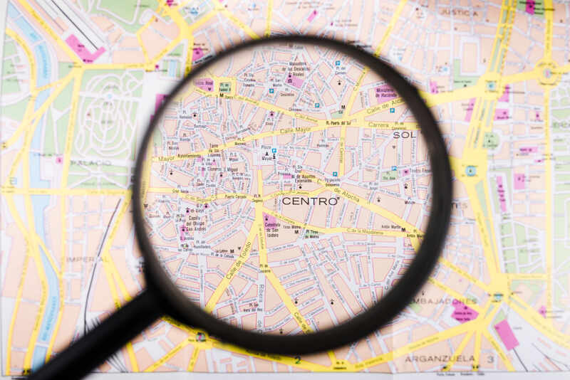 Lupa ampliando um mapa detalhado de uma cidade, com o foco na palavra 'CENTRO', simbolizando a busca precisa por soluções, a atenção aos detalhes e a localização conveniente para o cliente. A imagem representa a capacidade da Órion Farmácia de Manipulação em identificar e atender às necessidades específicas de seus clientes com precisão e foco, oferecendo acesso facilitado aos seus produtos e serviços.